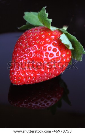 Ripe strawberry on black wet plate.