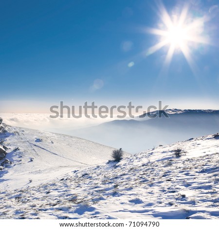 Beautiful landscape with snow-covered mountains, the sun and clouds