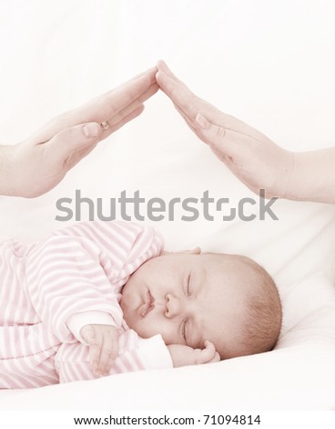hands of parents combined by a small house over the sleeping baby. The concept of care of children.