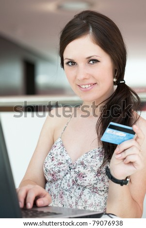 girl pays purchase through the Internet, sitting in cafe in shopping center