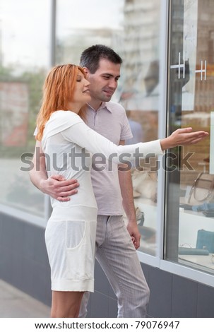 married couple to stand at a shop show-window. The woman shows on the pleasant thing.