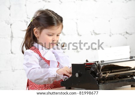 three-year girl prints on the old typewriter