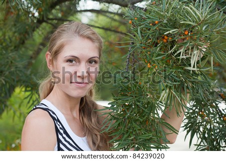 young woman near a bush of sea-buckthorn berries with fruits