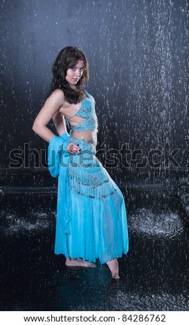 girl executes east dance in the rain against a dark background