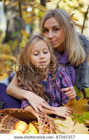 Happy mum and the daughter play autumn park on the fallen down foliage