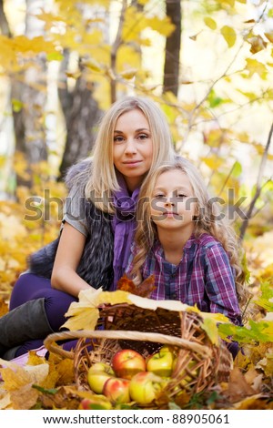 Happy mum and the daughter play autumn park on the fallen down foliage