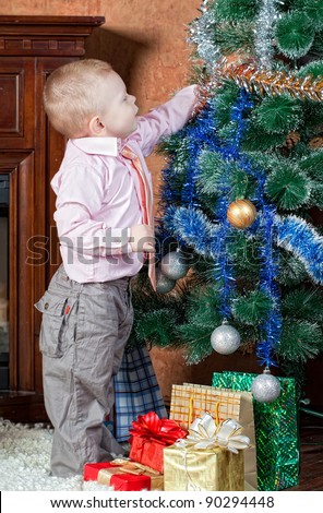 little boy dresses up a Christmas fur-tree