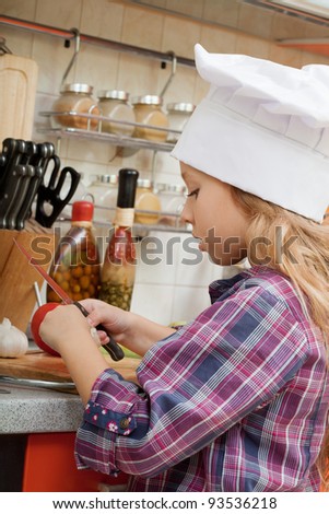 girl in a chef cap helps to make a dinner.