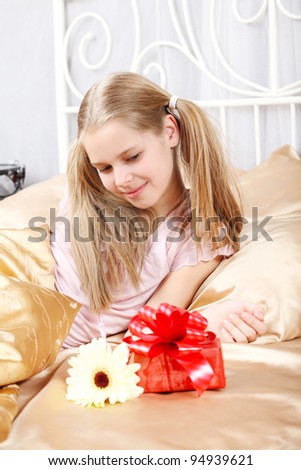 beautiful ten years\' girl has seen in bed a gift on birthday.