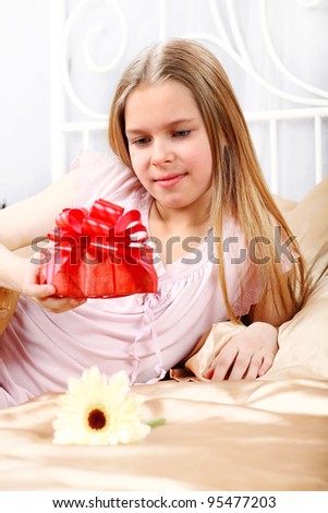 beautiful ten years' girl has seen in bed a gift on birthday.