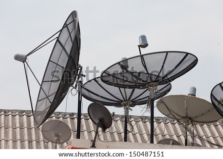 It is a lot of television satellite antennas on a house roof against the sky