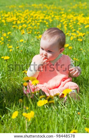 little girl in a pink dress plays to a glade with dandelions