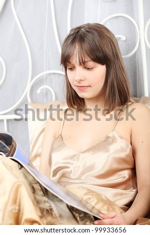 beautiful girl reads magazine lying in a bed