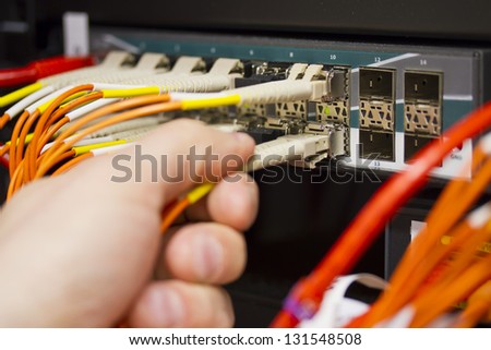 Insert a fiber cable into a switch in datacenter.