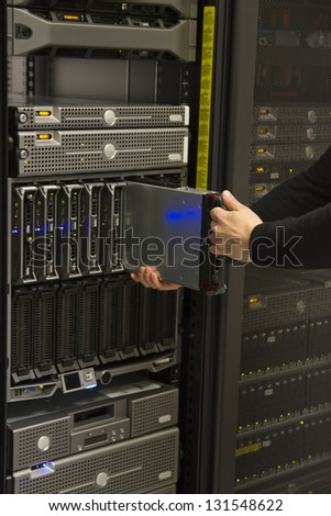 Install or remove a server in a blade chassis in a rack. Shot in a data center.