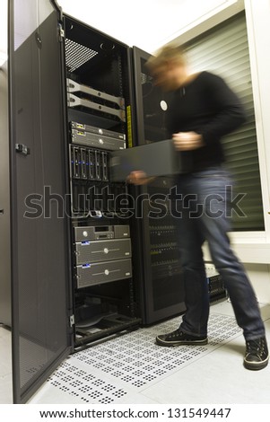 A fast working IT engineer / technician installing a server in a rack at the data center.