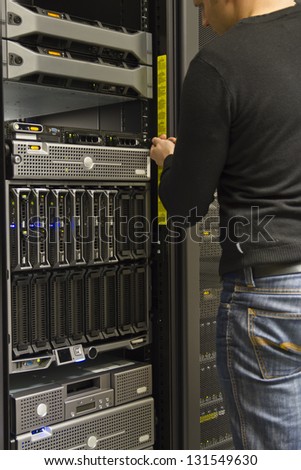 A working IT engineer / technician installing a server in a rack at the data center.