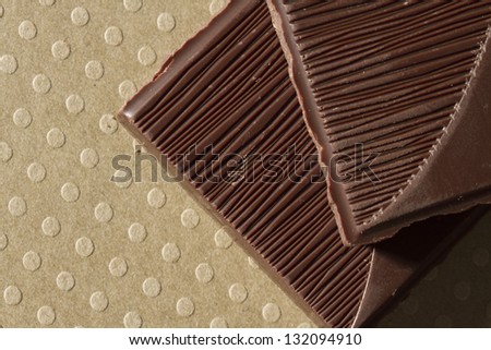 Close-up of dark chocolate piece on dotted ground.