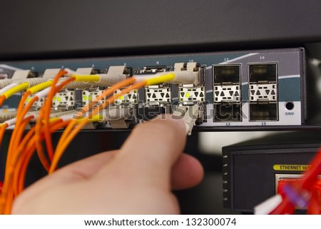 Insert a fiber cable into a switch in datacenter.