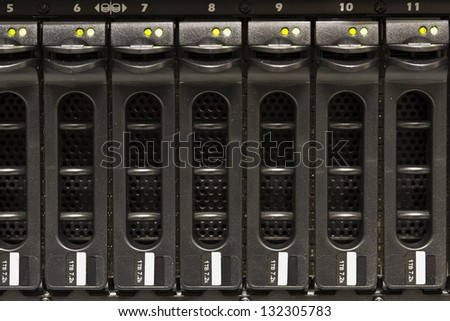 A disk cabinet / SAN with many large hard drives mounted in a rack. Shot in a data center.