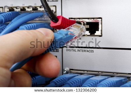 Close up of a consultant inserting a cat 5 / 5e / 6 patch cable into a PBX (Private Branch Exchange) switch station for telephone systems.