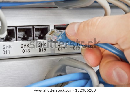 Close up of a IT consultant inserting / connecting a network / telephone cable into a patching panel.