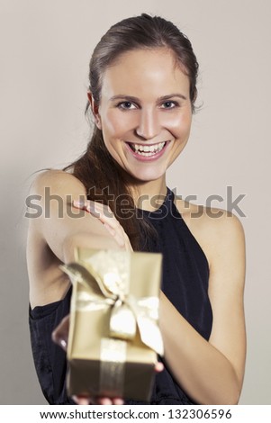 Smiling young woman give a christmas gift or birthday / valentines day present. Toned background.