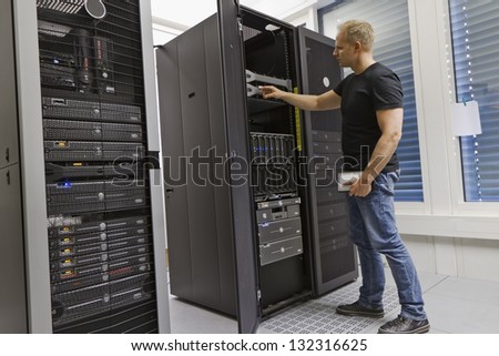 It engineer / consultant working in a data center. Holding a hard drive and opning a server.