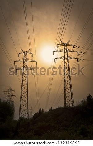 Green Energy: Electric power lines in the sunset. Electricity pylons and lines in the forest.