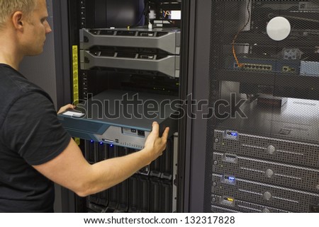 It engineer / consultant install / inserts a router / switch in a rack. Shot in a data center.
