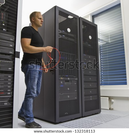 It engineer / consultant working in a data center. Holding a ethernet (Cat 5 / 6) cable.