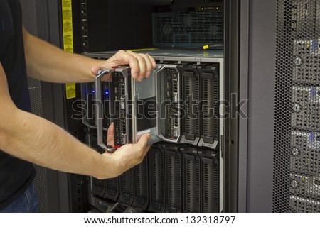 It engineer / consultant install / inserts or removes a blade server in a blade chassis in a rack. Shot in a data center.