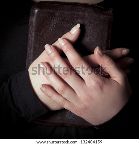 A close-up of a christian woman pray. Holding a Cross over a bible. Toned.