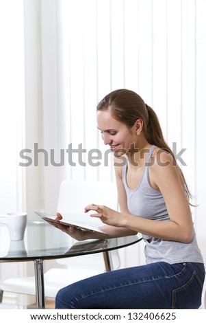 Woman drinking coffee and using pad in a white room. Copy Space