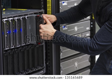 Install or remove a blade server in a blade chassis in a rack. Shot in a data center.