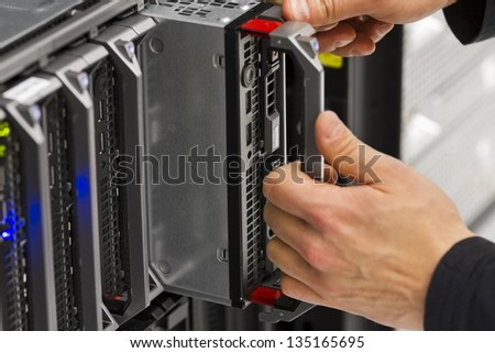 Install or remove a blade server in a blade chassis in a rack. Shot in a data center.