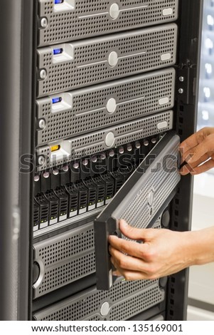 It engineer / consultant working in a data center. Holding a disk cabinet front and look at the disks. This enclosure in a SAN (storage area network).