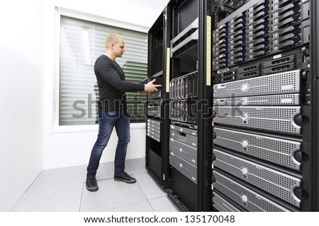 It engineer / consultant wokring and install / inserts a router / switch in a data rack. Shot in a data center.
