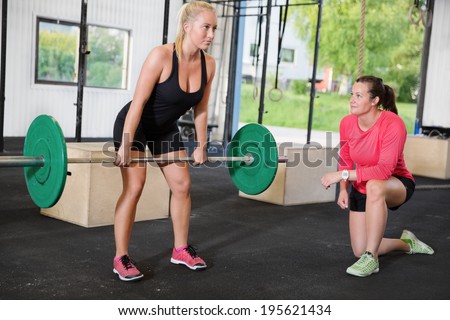 Crossfit woman lifts weights with personal trainer