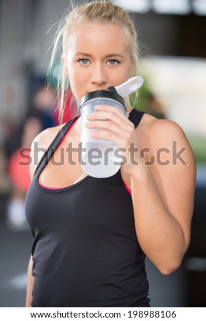 Blonde girl drinks water at fitness gym center