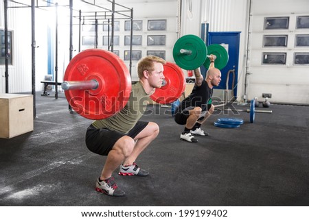 Team trains squats at fitness gym center