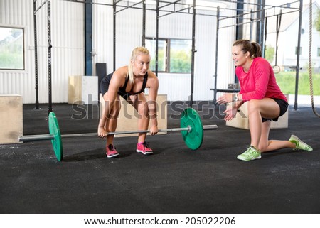 Crossfit woman lifts weights with personal trainer