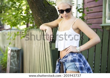 Blonde teenage girl model in front of wooden house