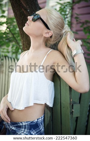 Young blonde woman in front of wooden fence