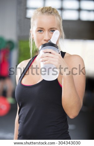 Attractive woman drinking water at fitness gym