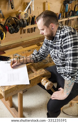 Carpenter plans projects and takes notes on drawing in workshop