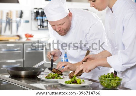 Smiling professional chef prepare steak dish at restaurant
