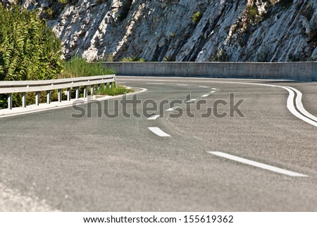 Curvy asphalt road with stone rocks in background.