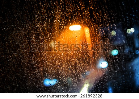 Rain drops on the window with dark streets outside and street lights shining