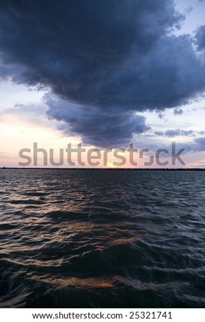 Dark clouds over Lake Erie at sunset. The dark water reflects the colors from the sunset.